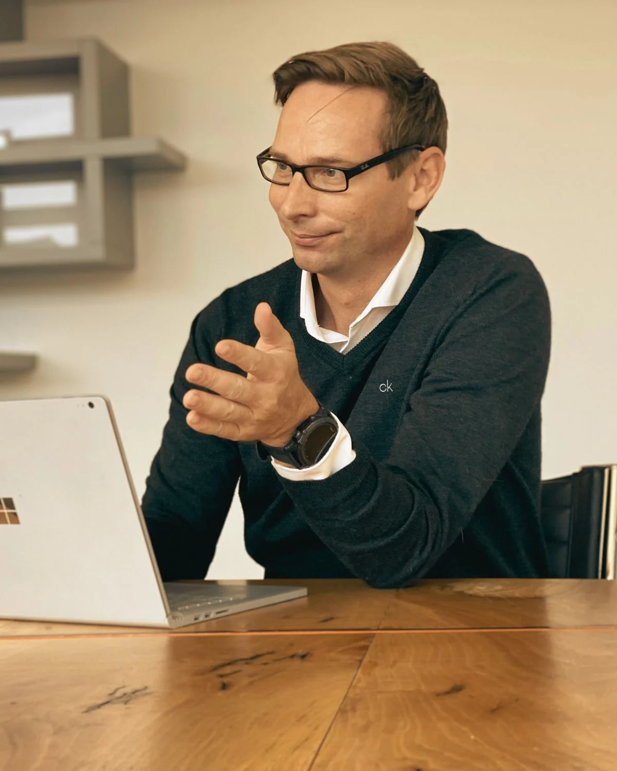 Andre Achtermeier at a meeting table, gesturing while he talks, with a laptop in front of him